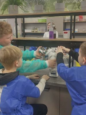 tr&oacute;jka uczni&oacute;w podczas obsługi urządzenia badającego powietrze