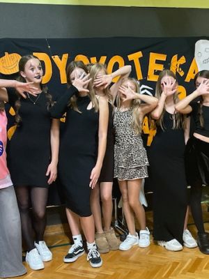 Uczestnicy dyskoteki robią sobie zdjęcie na ściance.