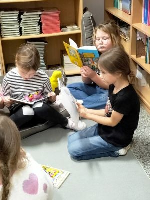 Dzieci w bibliotece szkolnej czytają bajki i baśnie. 