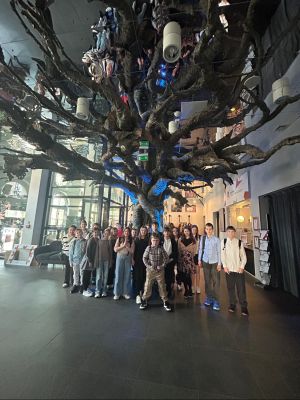 Uczniowie klas czwartych w holu teatru na tle wielkiego drzewa.