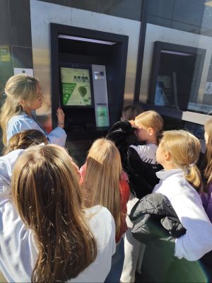 Uczniowie klasy 3a obserwują pokaz korzystania z bankomatu