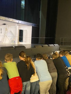 uczniowie obserwujący z widowni montaż scenicznych dekoracji