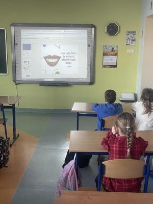 Uczniowie poznają zasady dbania o zęby podczas prezentacji w klasie.