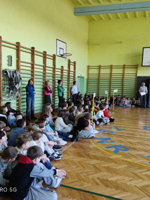 Uczniowie zgromadzeni na apelu w sali gimnastycznej szkoły. 