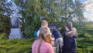 Uczniowie składają kwiaty i zapalają znicze na Cmentarzu Rzymskokatolickim w Strykowie.