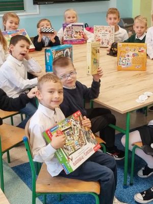 Uczniowie prezentują swoje ulubione gry planszowe, kt&oacute;re przynieśli z domu.