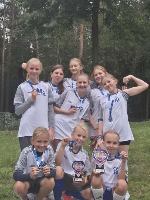 Drużna ze Strykowa z pucharem i medalami na najwyższym podium . 